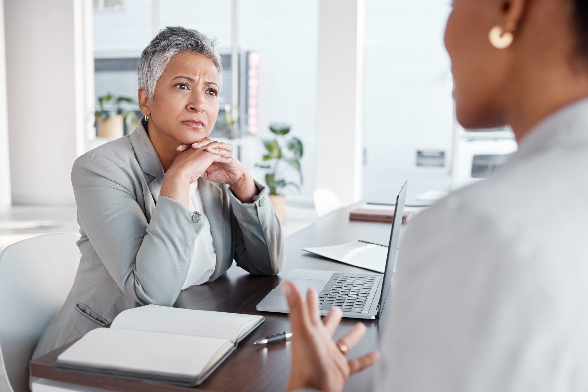 Concerned client listens to an Edmonton accident injury lawyer explaining details across a desk with a laptop and notebook.